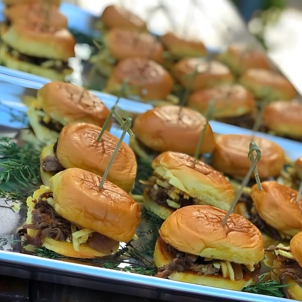Close-up of Cubavana Cafe's Cuban sliders with shredded meat and fries on a platter.