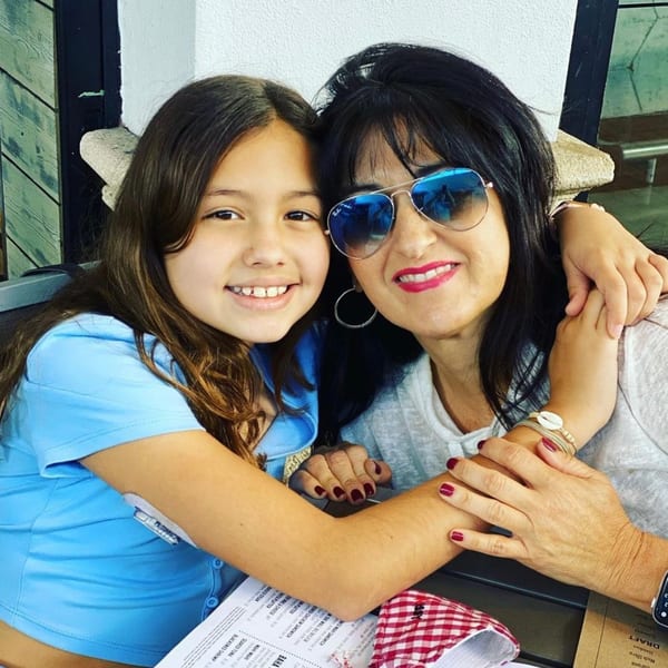 A smiling woman in sunglasses and a young girl embrace at a table in Cubavana Cafe.