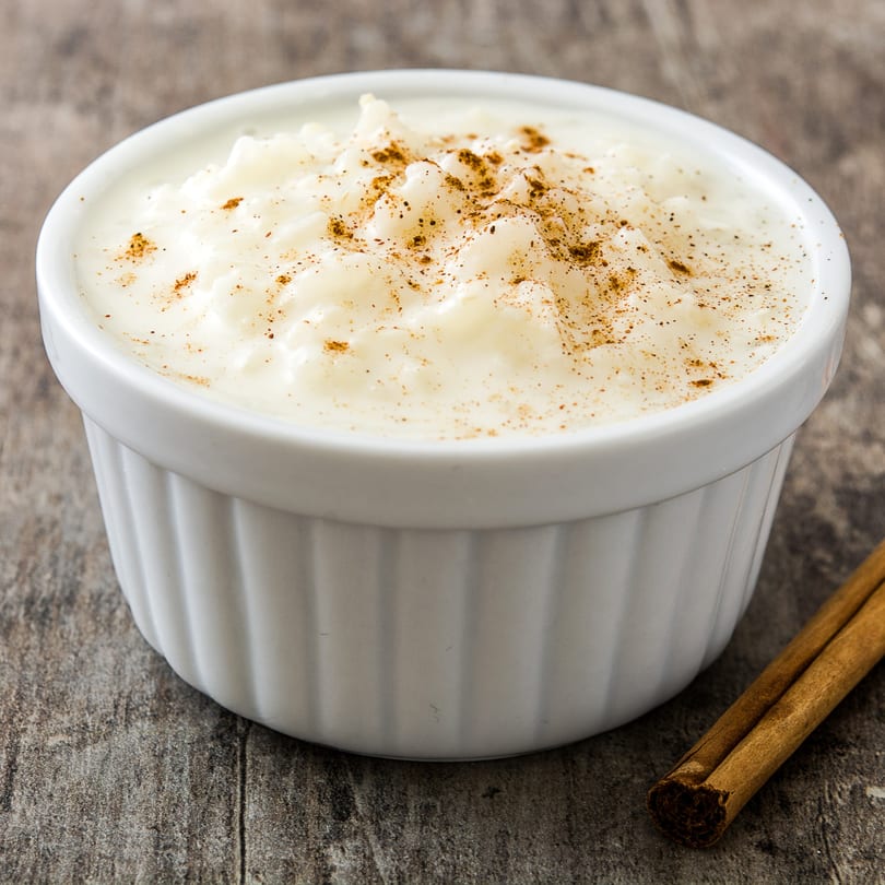 Cuban arroz con leche, a creamy rice pudding dessert, topped with cinnamon in a white bowl.